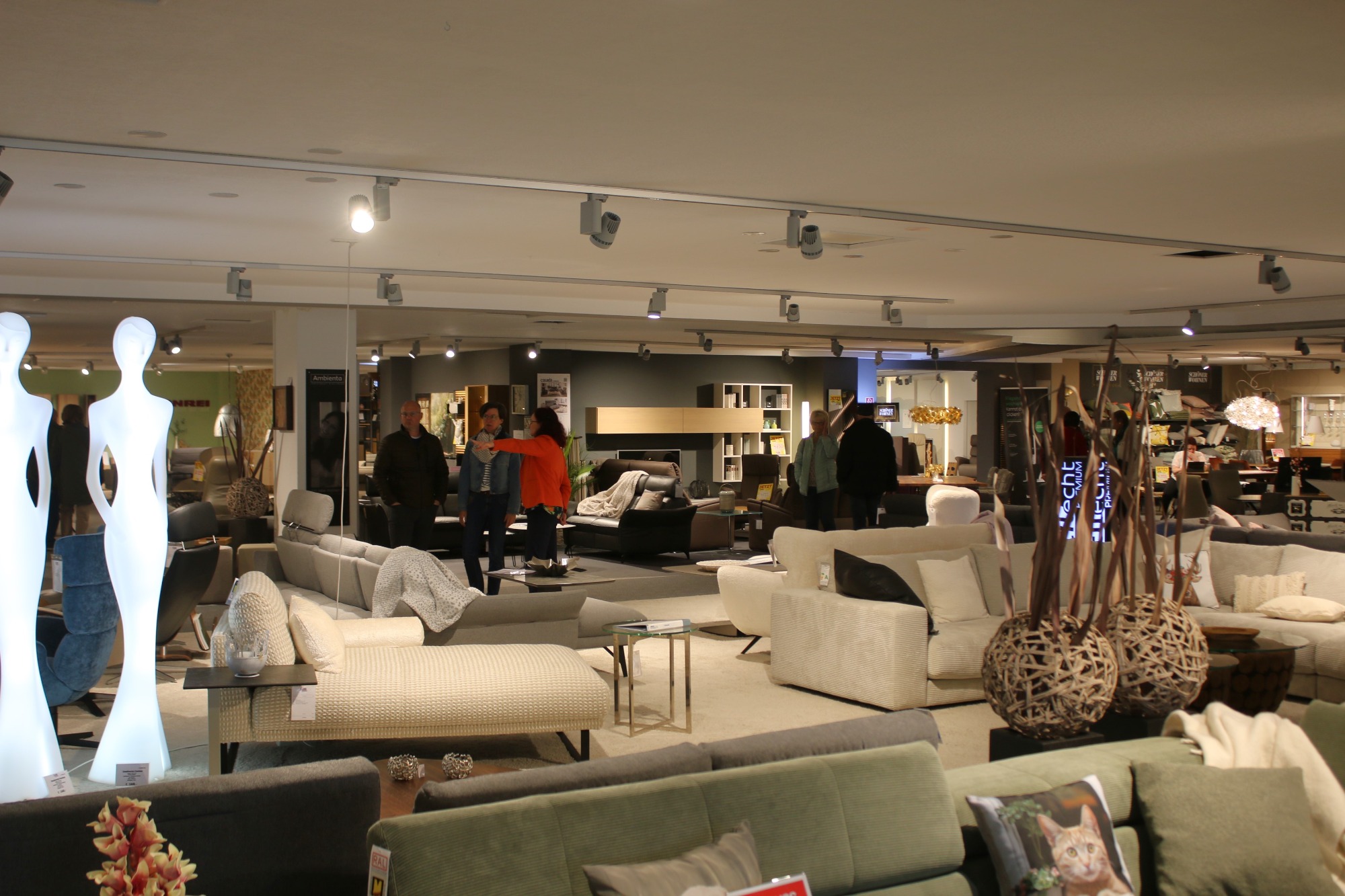 Möbelgeschäft mit modernen Sofas, Deko-Artikeln und mehreren Kunden im Raum.