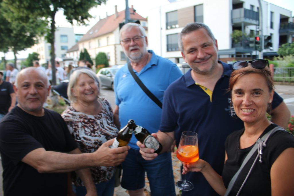 Fünf Personen stehen zusammen, lächeln und halten Getränke in der Hand.