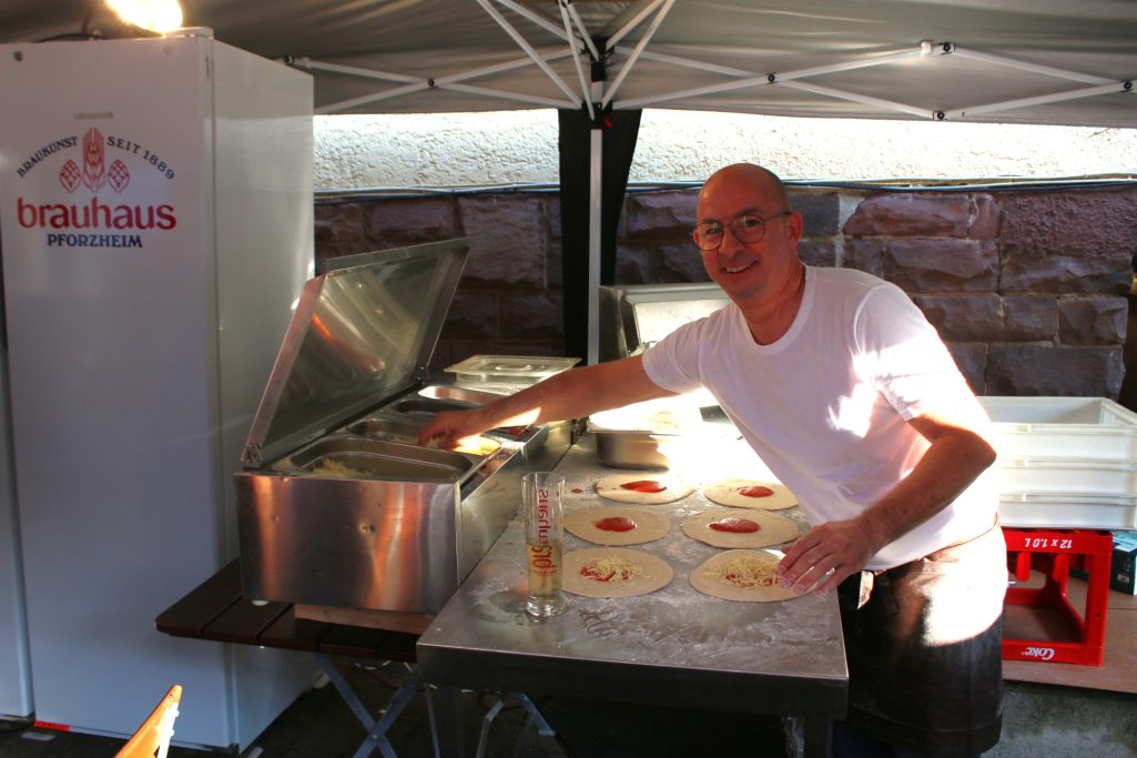 Ein Mann bereitet Pizzen an einem Verkaufsstand im Freien vor.