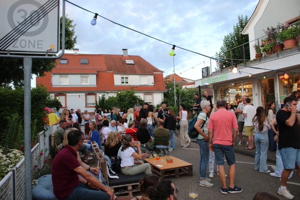 Viel Menschen bei einer Feier im Freien, mit Ständen und hübschem Wetter.