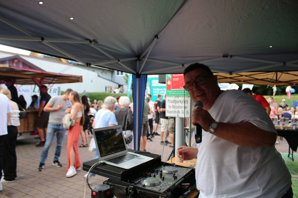 DJ am Mikrofon, der eine Menschenmenge bei einer Veranstaltung unterhält.