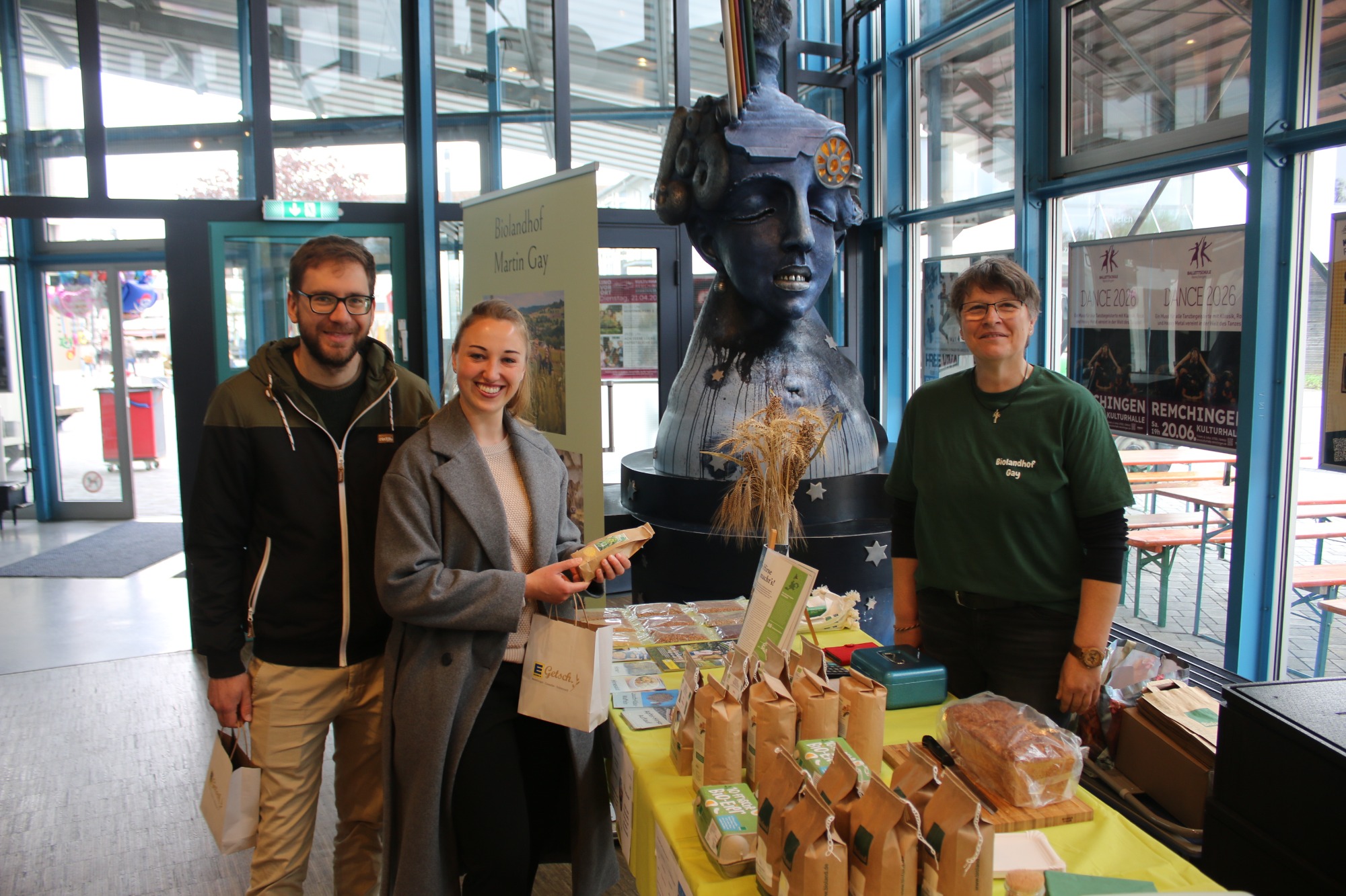 Drei Personen stehen an einem Tisch mit verpackten Lebensmitteln in einem Geschäft.