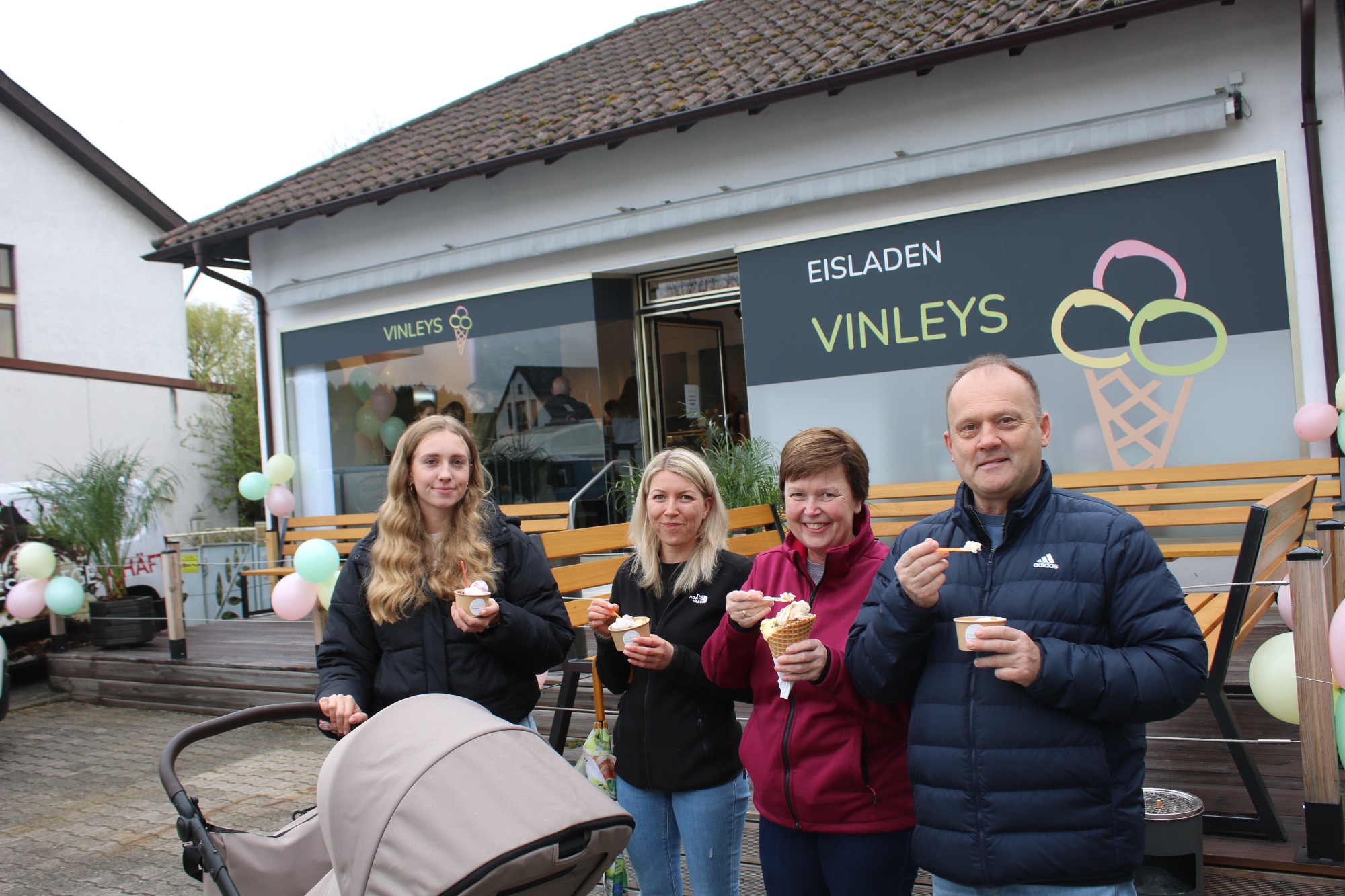 Grupp von vier Personen mit Eis in der Hand vor einem Eiscafé.