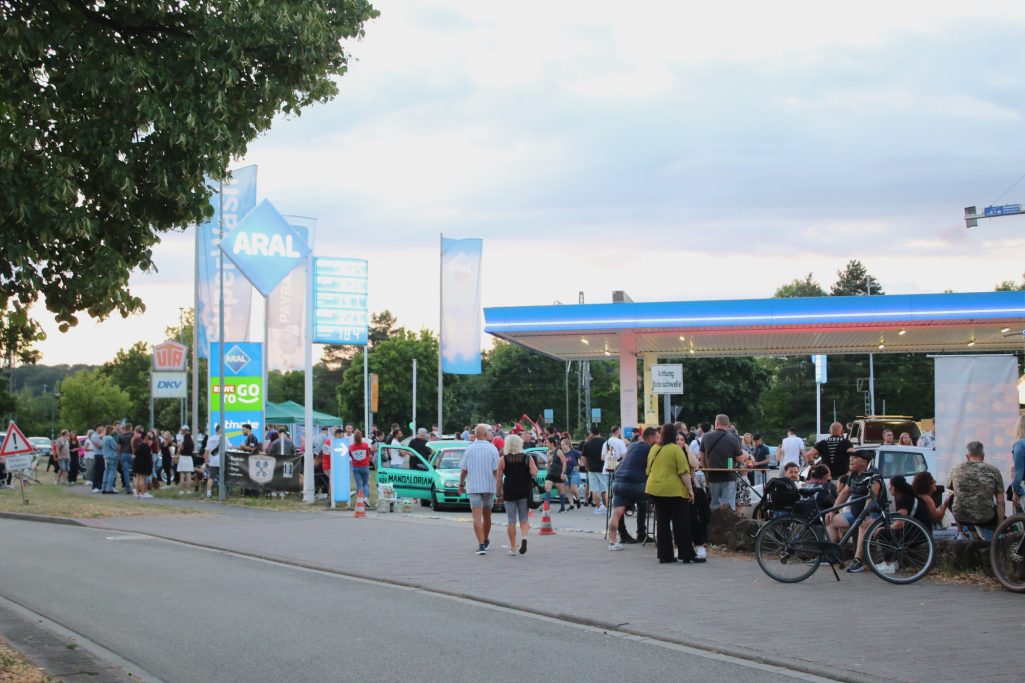 Menschenmenge an einer Tankstelle, viele stehen in Schlangen, um zu tanken.