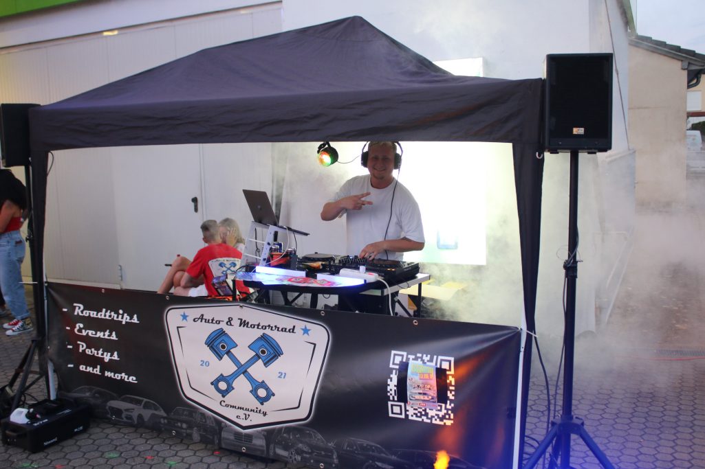 DJ an einem Pavillon mit Lautsprechern und Lichtern, Musik wird gespielt.