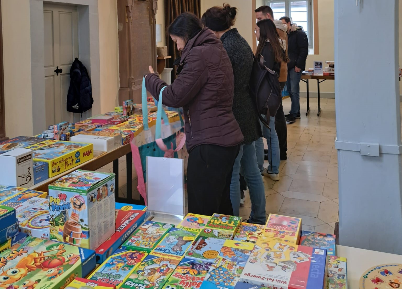 Menschen wählen aus verschiedenen Brettspielen auf einem Basar aus.